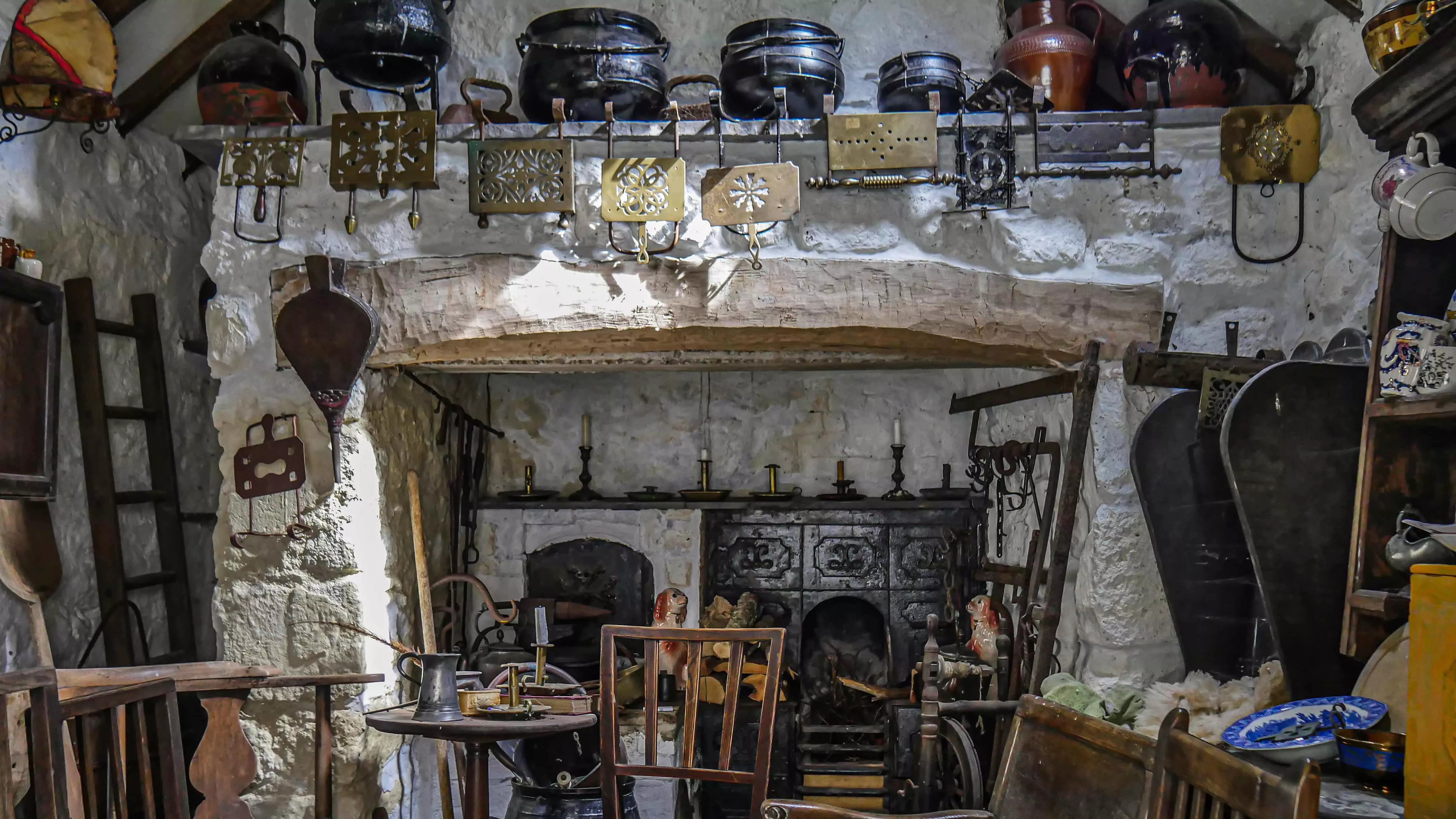 photo of one of the outbuildings, in the centre is an old cooking range surrounded by antique country furniture