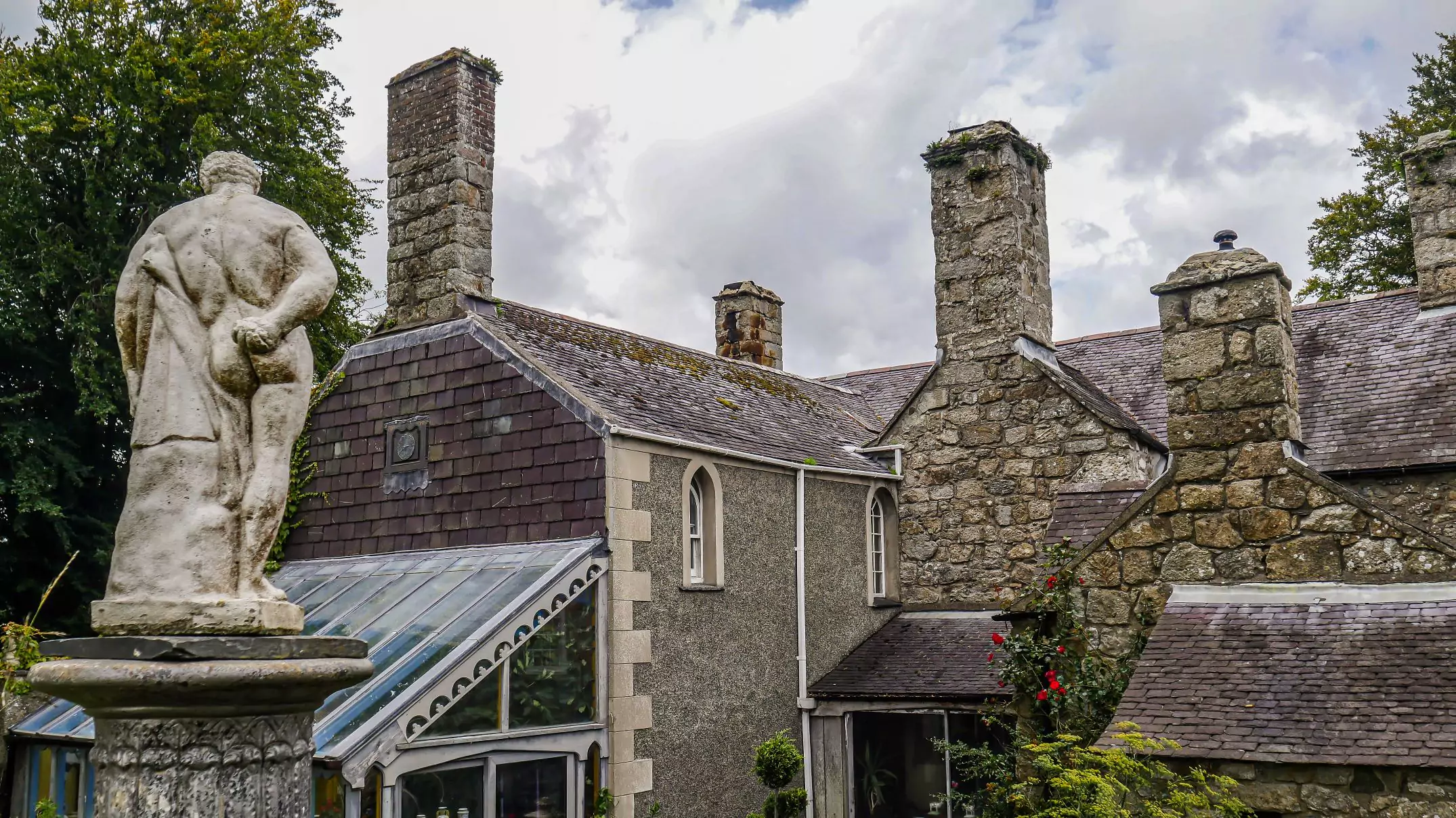 photo showing the rear view of the house, in the foreground is a statue of hercules